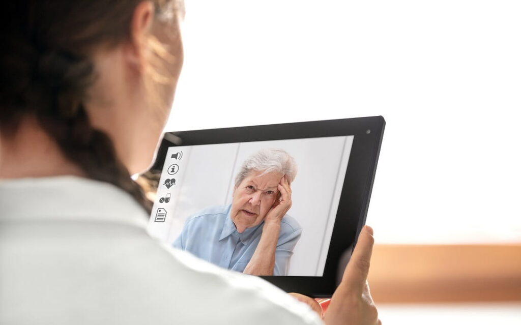 Ärztin schaut auf den Bildschirm im Gespräch mit einer Seniorin