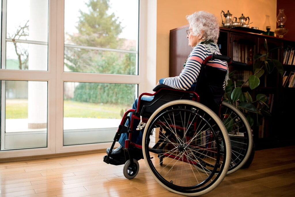 Seniorin im Rollstuhl schaut aus dem Fenster