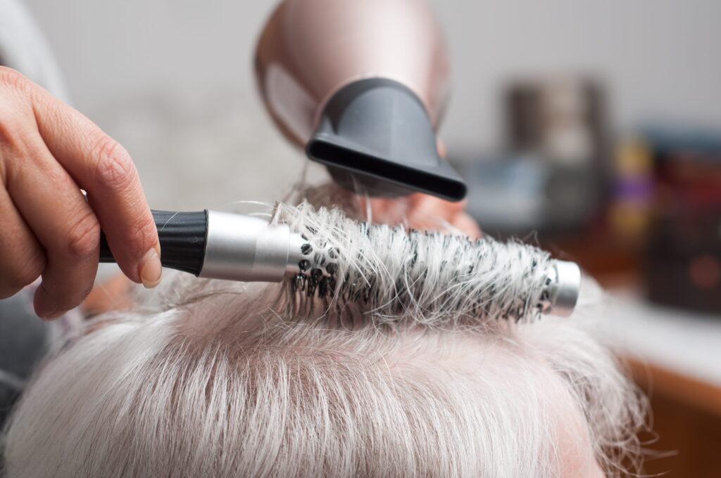 Frauenhände machen älterer Dame die Haare