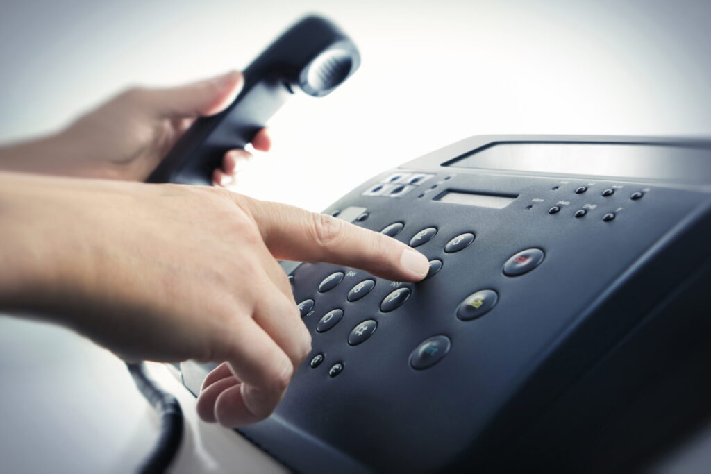 Hand wählt Nummer auf Telefon
