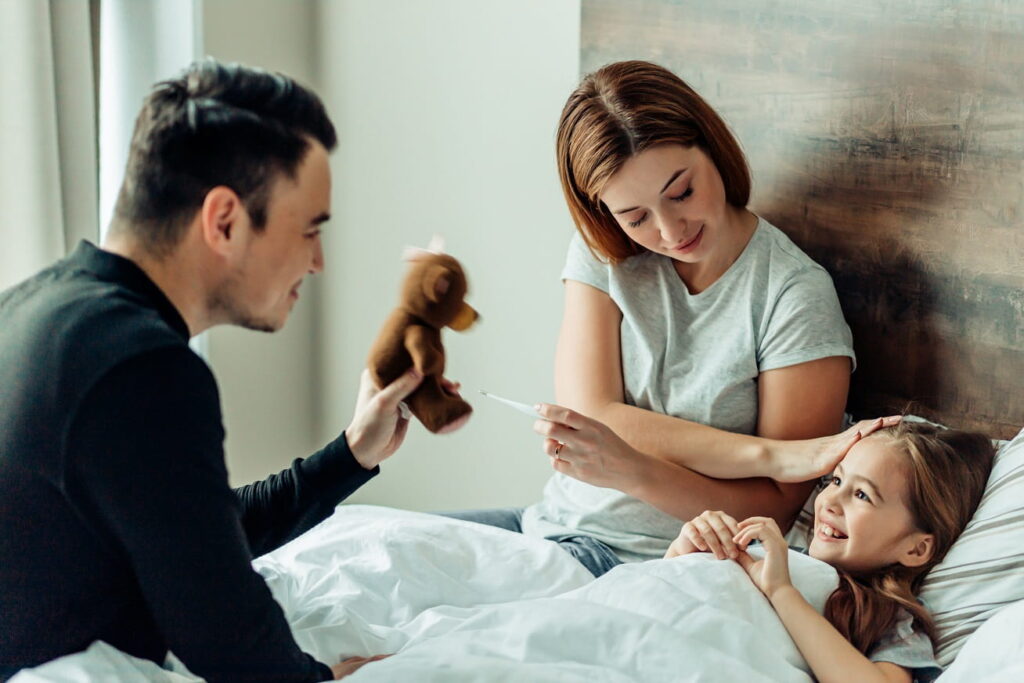 Eltern sitzen am Bett ihrer kranken Tochter