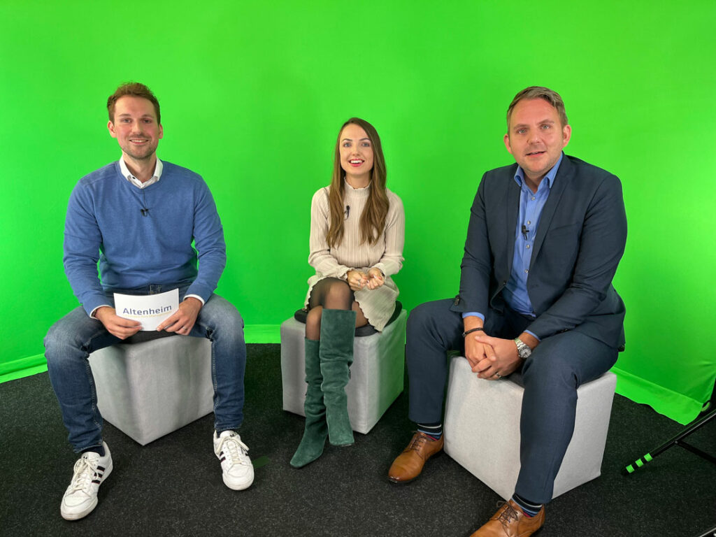 Drei Personen sitzen vor einem grünen Hintergrund