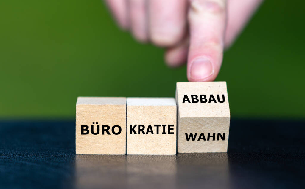 Hand dreht Würfel und ändert den Ausdruck Bürokratiewahn in Bürokratieabbau.