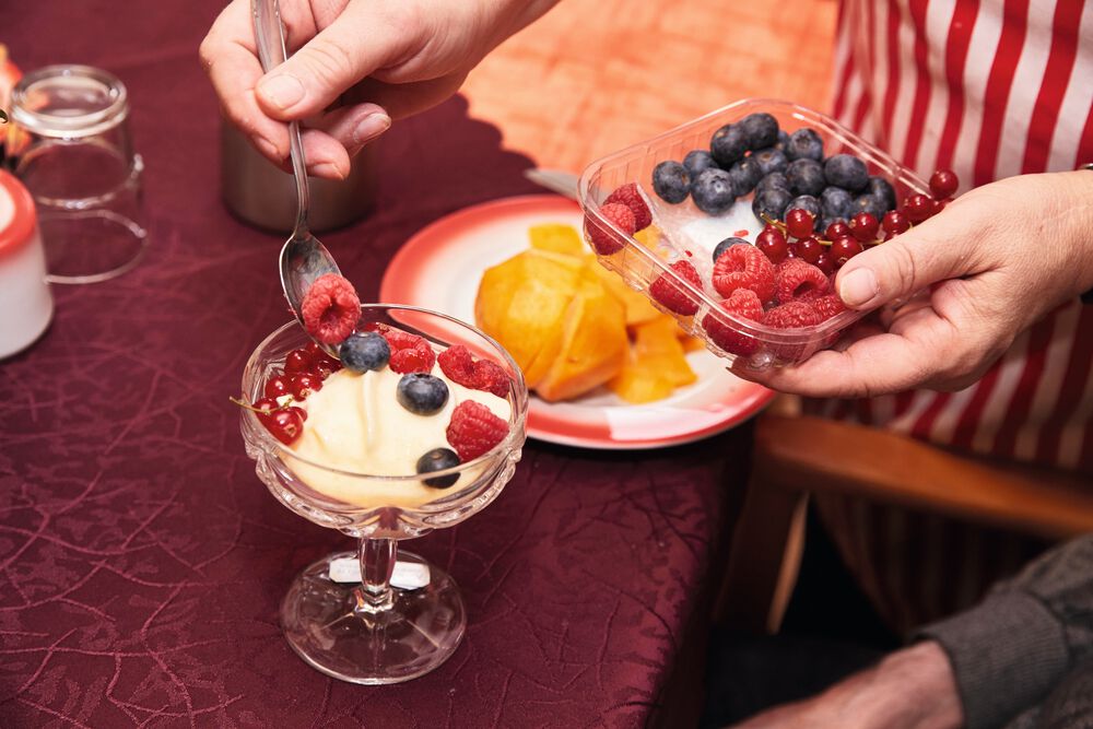 Ein Pudding-Dessert wird mit Waldfrüchten belegt.