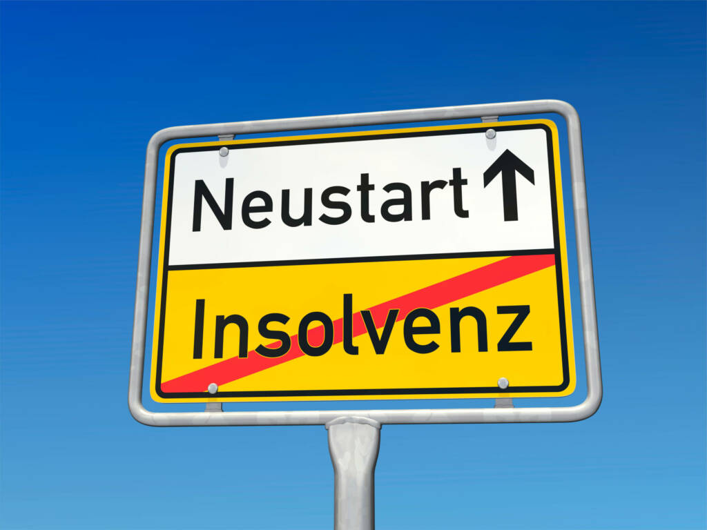Ortsschild mit "Neustart" und durchgestrichenem "Insolvenz", symbolisiert wirtschaftlichen Neuanfang vor blauem Himmel.