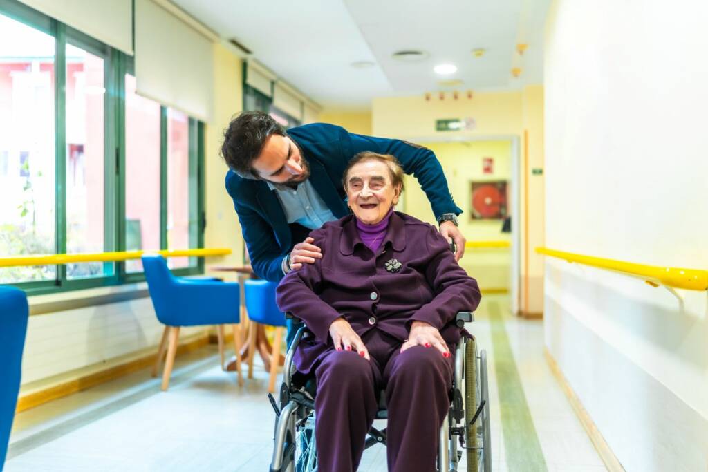 Nurse assisting elderly woman in wheelchair at retirement home